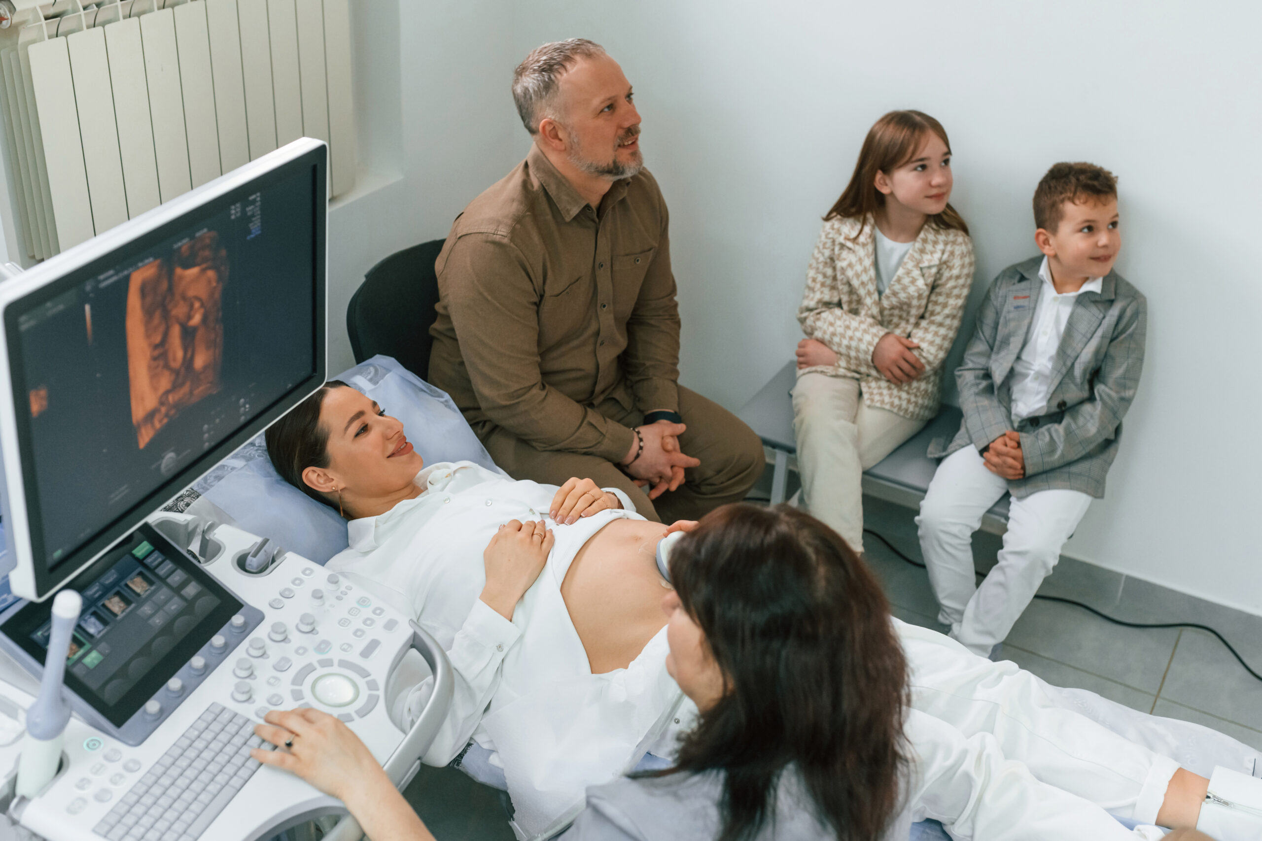 Family is sitting together. Pregnant woman is lying down in the hospital, doctor does ultrasound.